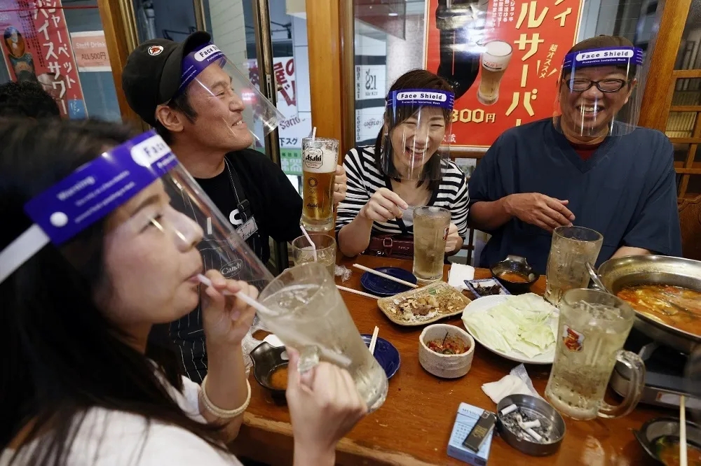 图片说明:5月25日,在日本大阪,人们佩戴防护面罩聚餐(来源:新华社)